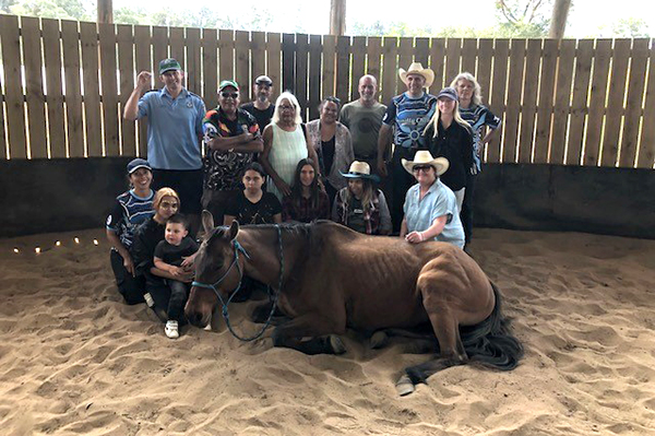 Adrian Feirer with Equiten Spirit Healing project participants and horse in a sand arena
